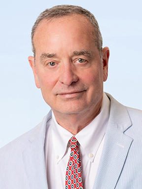 A man wearing a seersucker suit, white dress shirt and red patterned necktie on a light blue background.