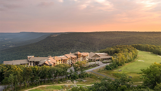 Scenic resort enveloped by towering mountains and vibrant trees, creating a tranquil and inviting atmosphere.