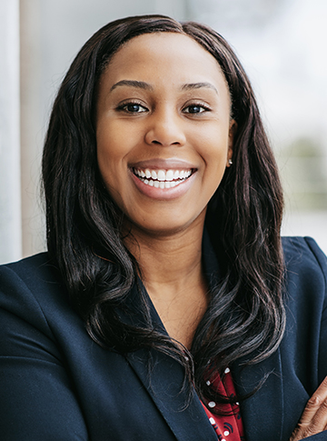 Young woman with long hair wearing a blue blazer and smiling.